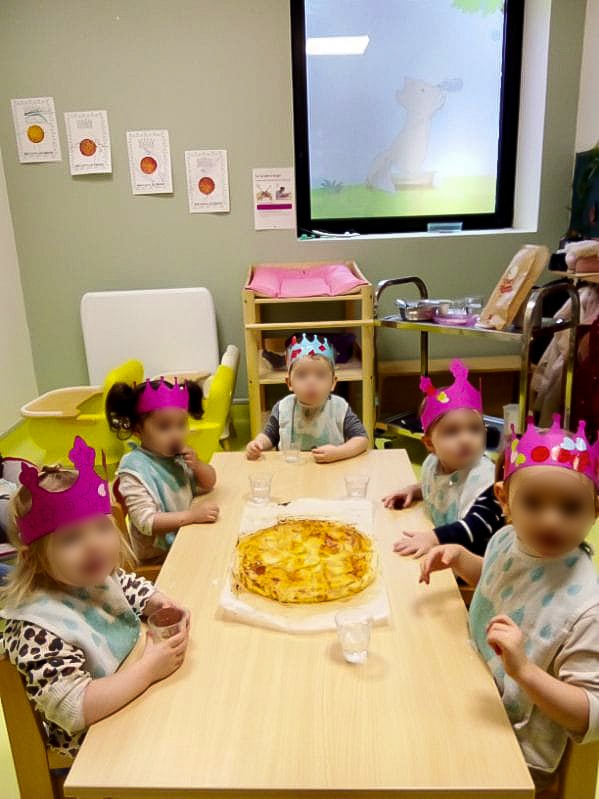 Les enfants dégustent la galette des rois ensemble à la crèche.