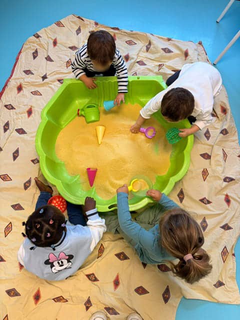 Des enfants jouent avec un bac à semoule à la crèche.